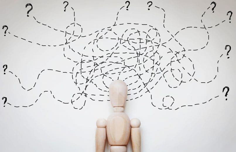 A wooden man with scribbles around his head representing thought patterns.